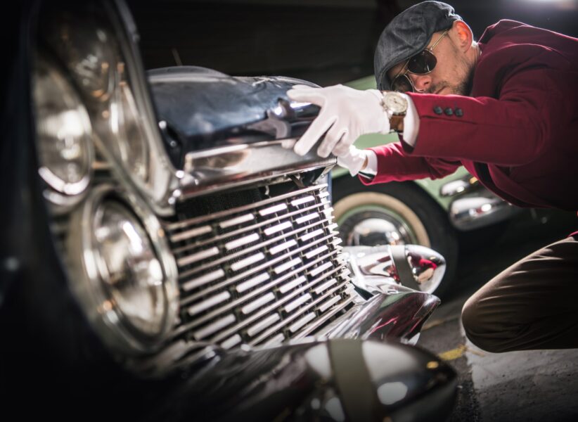 Classic Car Collector Evaluation. Caucasian Men Taking Close Look on the Vintage American Vehicle For Sale.
