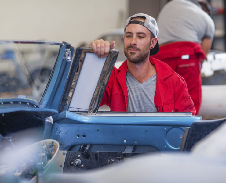 Mechanics restoring vintage cars in workshop Mechanics restoring vintage cars in workshop