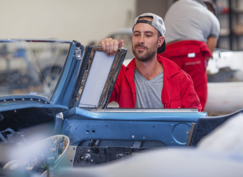 Mechanics restoring vintage cars in workshop