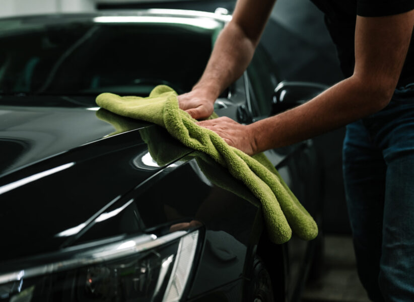 man cleans the car body with a towel. auto care.