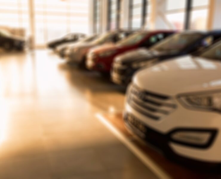 Stock of cars in showroom of automobile dealer with sunlight from window. Blurred