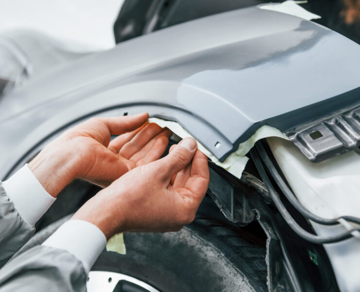 Detailed work. Caucasian automobile repairman in uniform have job in garage.