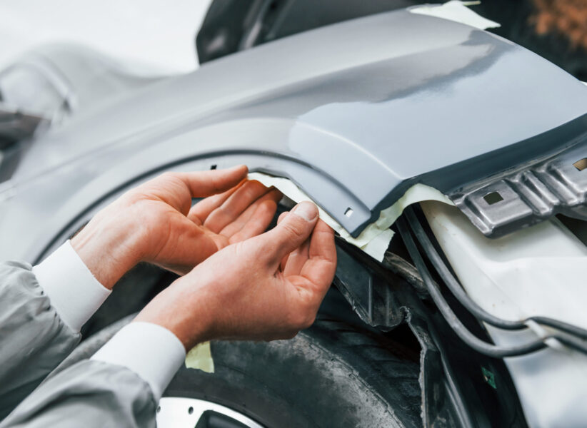 Detailed work. Caucasian automobile repairman in uniform have job in garage.